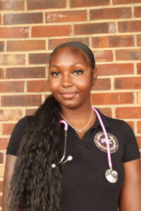 Kiera has hair over shoulder and stethoscope with pink cord.